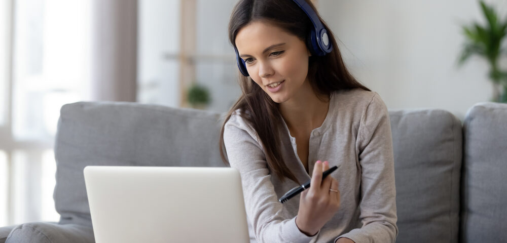 Happy,Young,Woman,In,Headphones,Speaking,Looking,At,Laptop,Making