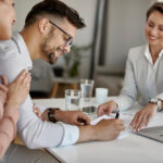 1 uomo-felice-e-sua-moglie-che-hanno-un-incontro-con-il-consulente-finanziario-e-firmano-un-accordo-in-ufficio